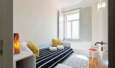 a room with a bed with yellow pillows and a window at A da Maria Ildefonso in Porto