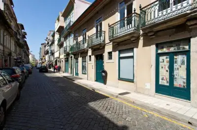 a cobblestone street in a city with buildings and cars at A da Maria Ildefonso in Porto