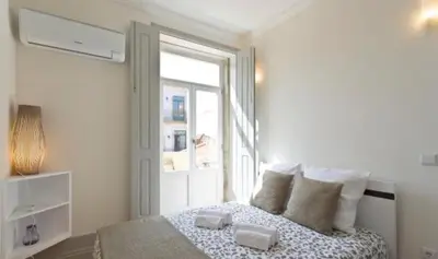 a white bedroom with a bed and a window at A da Maria Ildefonso in Porto