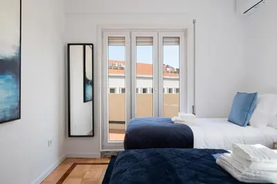 a bedroom with two beds and a large window at Poveiros Terrace - 3BR Downtown apartment with AC in Porto