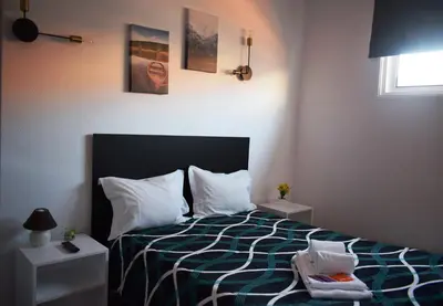 a bedroom with a bed with a green and white comforter at Guest House Henrique VIII in Porto