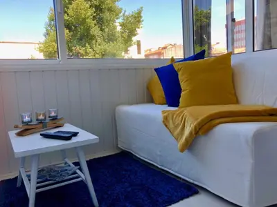 a white couch with yellow and blue pillows and a table at L&M Apartment in Porto