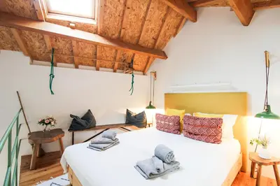 a bedroom with a large white bed and wooden ceilings at Macário Cosy Loft in Porto