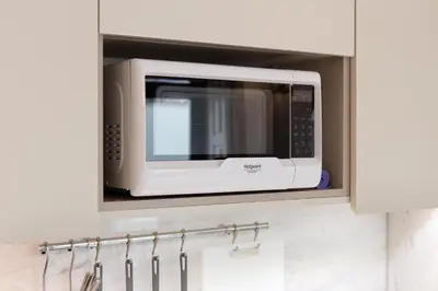 a microwave in a cabinet in a kitchen at CASA JOY Boavista apartment in Porto