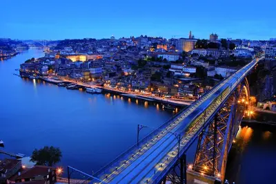 a bridge over a river with a city at night at SLEEPBOAT Barco Hotel in Porto