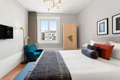 a bedroom with a large bed and a blue chair at The White Box Boutique House in Porto