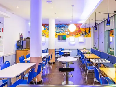 a dining room with tables and blue chairs at Hotel ibis Budget Porto Gaia in Vila Nova de Gaia