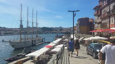 a group of people walking along a dock with boats at Historic Oporto Apartment at oporto UNESCO area, in front of Porto Wine caves in Porto