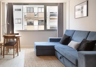 a living room with a blue couch in front of a window at Marquês Deluxe Apartment in Porto