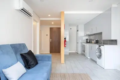 a living room with a blue couch and a kitchen at Marquês Deluxe Apartment in Porto