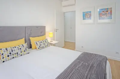 a bedroom with a large white bed with yellow pillows at Luxury Anibal Cunha Apartments in Porto