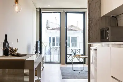a kitchen with white cabinets and a large window at Casa D'ouro in Porto
