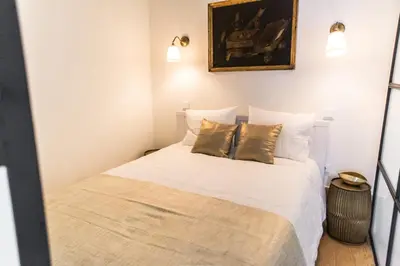 a bedroom with a bed with white sheets and gold pillows at Casa D'ouro in Porto