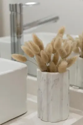 a white vase filled with feathers sitting on a counter at Casa da Luz - Lighthouse of Porto in Porto