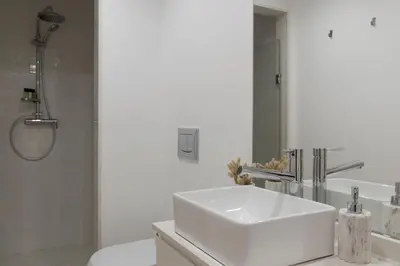 a white bathroom with a sink and a shower at Casa da Luz - Lighthouse of Porto in Porto