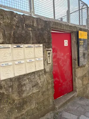 a red door on the side of a stone building at By this River in Porto