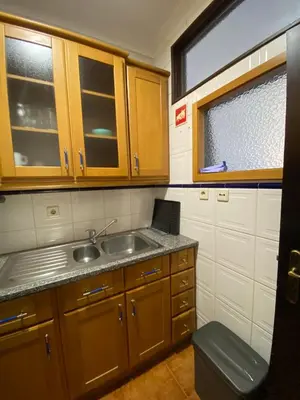 a kitchen with wooden cabinets and a sink and a window at Casa dos Azulejos in Porto