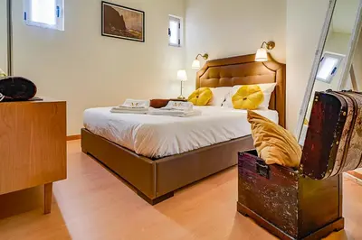 a bedroom with a bed with a mirror and a suitcase at Port Wine Flats in Vila Nova de Gaia