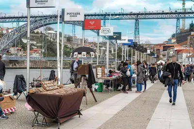 a group of people walking down a street with a bridge at Port Wine Flats in Vila Nova de Gaia
