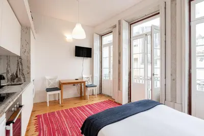 a white bedroom with a bed and a desk and windows at VIVA Breiner Flats in Porto