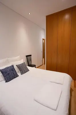 a bedroom with a white bed and a wooden cabinet at Downtown Porto Relaxed Apartment with Private Yard in Porto