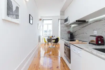 a kitchen with white walls and a wooden floor at Host Wise - Colorful Stunning Sunlit Flat in Porto