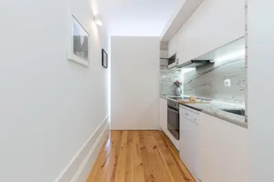 a kitchen with white walls and a wooden floor at Host Wise - Colorful Stunning Sunlit Flat in Porto