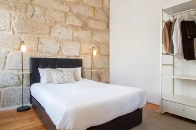 a bedroom with a white bed and a brick wall at LovelyStay - Aurora Mezzanine in Porto