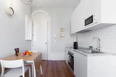 a kitchen with a sink and a table with a bowl of fruit at Host Wise - Charming Flat with Netflix - River View in Porto