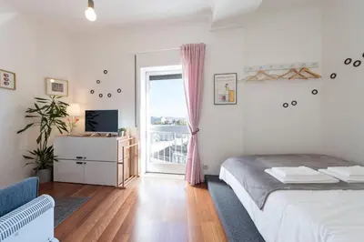 a bedroom with a bed and a window with a balcony at SP199 Flat by in Porto