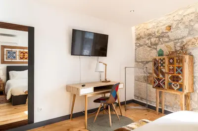 a bedroom with a desk and a tv on a wall at Tito Studio Terrace in Porto