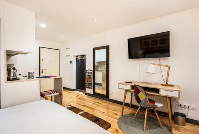 a bedroom with a bed and a desk and a tv at Tito Studio Terrace in Porto