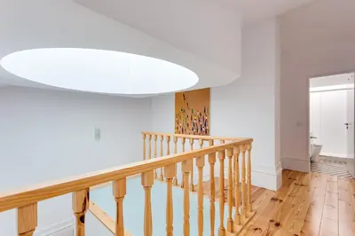 a white hallway with a wooden staircase with a white ceiling at Almada Luxurious Duplex by DA'HOME in Porto