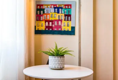 a potted plant sitting on a table in front of a painting at DA'HOME - Cedofeita Art Studio in Porto