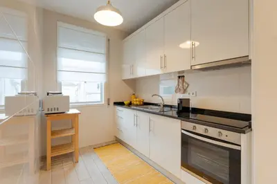 a kitchen with white cabinets and a sink at DA'HOME - Marquês Lovely 2BD Apartment in Porto
