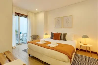a bedroom with a large bed and a balcony at DA'HOME - Marquês Unique Terraza in Porto