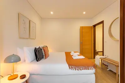 a bedroom with a bed and a table with a lamp at DA'HOME - Marquês Unique Terraza in Porto