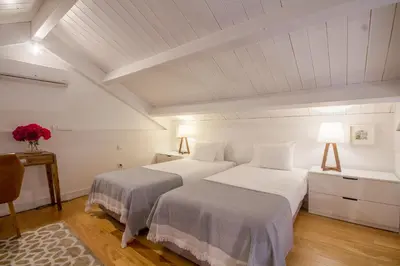 two beds in a room with white walls and wood floors at Comercio RIBEIRA Luxury Penthouse Apartment in Porto