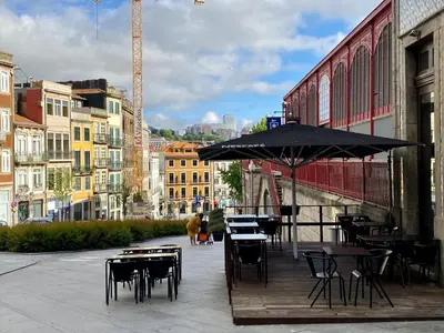 a patio with tables and chairs and an umbrella at Comercio RIBEIRA Luxury Penthouse Apartment in Porto