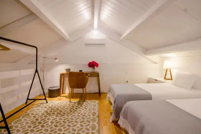 a bedroom with two beds and a desk and a table at Comercio RIBEIRA Luxury Penthouse Apartment in Porto