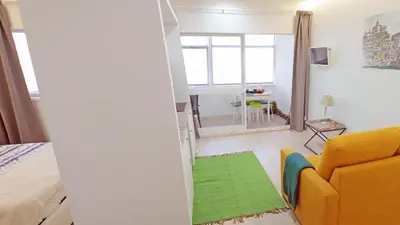 a living room with a yellow couch and a green rug at São João Oporto Residence I & II in Porto