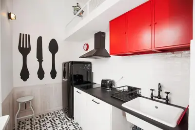 a small kitchen with red cabinets and a sink at GET Lights and Books in Flat in Porto