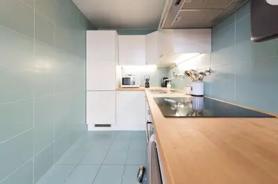 a kitchen with white cabinets and a counter top at Fontainhas Design Apartment by DA'HOME in Porto