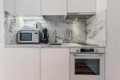 a kitchen with white cabinets and a microwave at Backyard Palace Terrace in Porto