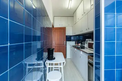 a blue tiled kitchen with a stool and a table at Casa do Antonio in Porto