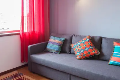 a gray couch with colorful pillows sitting next to a window at Casa do Antonio in Porto