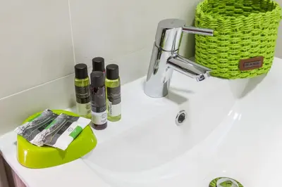a bathroom sink with a faucet and a green basket at Casa do Antonio in Porto