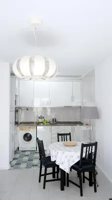 a white kitchen with a table and chairs and a chandelier at Gaia Central Apartment in Vila Nova de Gaia