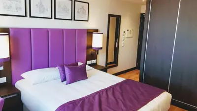 a bedroom with a purple headboard and a bed at Porto City Hotel in Porto