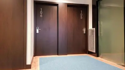 a hallway with two brown doors with a blue rug at Porto City Hotel in Porto
